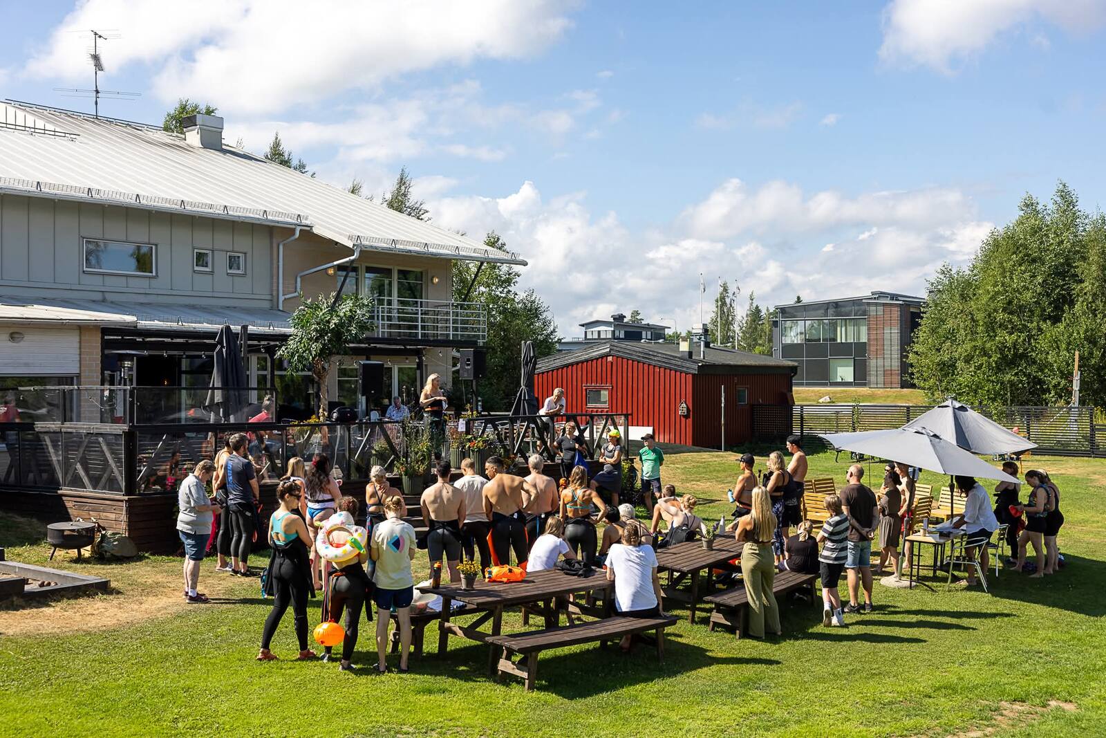 Festivalpublik samlad kring picknickbord på gräset vid älven